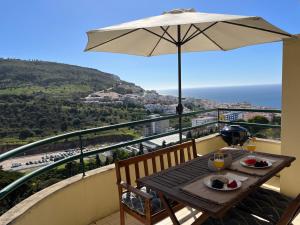 una mesa con sombrilla en el balcón en Casa do Mar - Sea view - Wifi - Barbecue, en Sesimbra