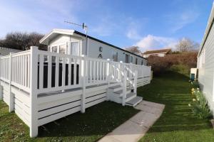 a white house with a porch and a white fence at The Willows in Selsey