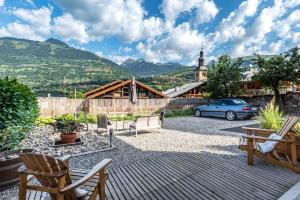 a patio with chairs and a car and a church at Maison Lennox in Mâcot La Plagne