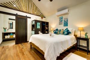 1 dormitorio con 1 cama blanca grande con almohadas azules en Azure Del Mar en Maya Beach