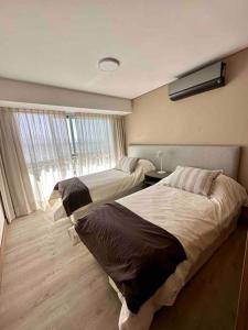 a hotel room with two beds and a window at Elegante departamento a estrenar 2 Dormitorios in Villa Marini