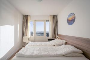 Un dormitorio con dos camas y una ventana. en Appartementencomplex Juliana 124, en De Koog