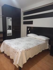 Hospedaje La Lisera Suite في تاكنا: غرفة نوم مع سرير كبير مع اللوح الأمامي الأسود