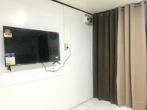 TV de pantalla plana colgada en una pared junto a una cortina en Central Hub Homestay, en Puerto Princesa City