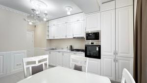 a white kitchen with white cabinets and a table and chairs at Luxury Residence Business New Apartments in Chişinău