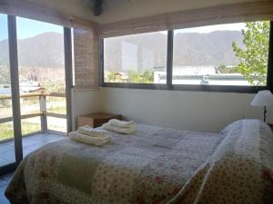 1 dormitorio con 1 cama con 2 toallas en La Antonia, cabaña al pie de la montaña en Luján de Cuyo