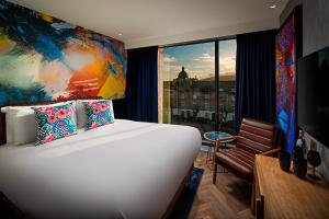 Un dormitorio con una gran cama blanca y una ventana en NYX Hotel Dublin Portobello en Dublín