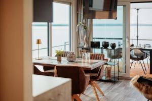 a dining room with a table and chairs with a view of the ocean at Hausboot Cosy Home - LP16 in Laasow