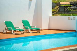 two green chairs sitting next to a swimming pool at Casa Pereira – Snooker, Wi-Fi, Bbq, Pool in Relógio do Poiso