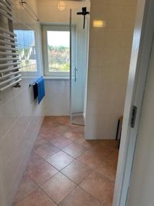a bathroom with a shower and a tiled floor at Loeiboei in Buren