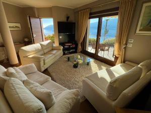 una sala de estar con muebles blancos y vistas al océano. en Pellegrini Boutique Villa Lake View, en Verbania