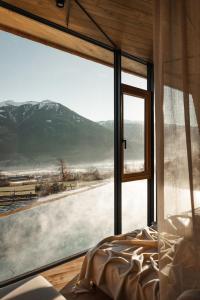 ein Schlafzimmer mit einem großen Fenster mit Blick auf einen verschneiten Berg in der Unterkunft ASTER Boutique Hotel & Chalets in Fügenberg