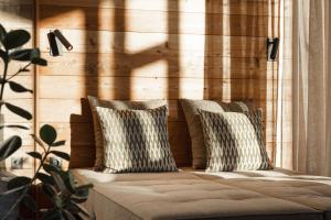 a couch with two pillows on a wooden wall at ASTER Boutique Hotel & Chalets in Fügenberg