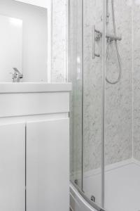 a white bathroom with a shower and a sink at KHAFAJI INN in East Barnet