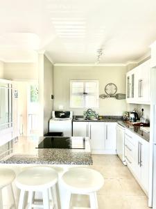 a kitchen with white cabinets and white stools at Elysian Retreat in Ballito