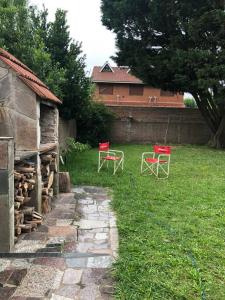 two red chairs sitting in the grass next to a house at Casa Santa Clara del Mar in Santa Clara del Mar