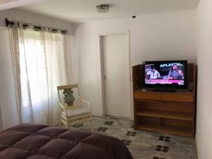 a bedroom with a bed and a tv and a chair at Casa Santa Clara del Mar in Santa Clara del Mar