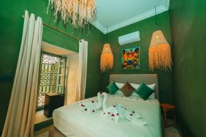 a bedroom with a bed with green walls and chandeliers at Hotel & Riad Veridis in Marrakech