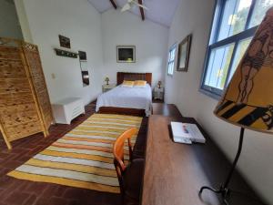 1 dormitorio con 1 cama y escritorio con lámpara en Sitio Carpir - conforto, charme e natureza a 2h de SP, en Paraibuna