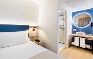 a bedroom with a white bed and a sink at Occidental Alicante in Alicante