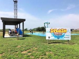 a sign in the grass next to a swimming pool at Beach Please in Surfside Beach