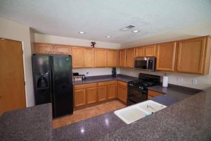 a kitchen with wooden cabinets and a black refrigerator at Home near Balloon Fiesta Park! in Albuquerque