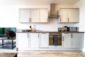 a kitchen with white cabinets and a sink at Central Swindon Gem Stylish 1-Bedroom Apartment in Swindon