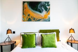 a bedroom with a bed with green pillows and a painting on the wall at Central Swindon Gem Stylish 1-Bedroom Apartment in Swindon