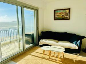 ein Wohnzimmer mit einem Sofa und einem Balkon in der Unterkunft Vue mer Appartement Le Miramar in La Baule