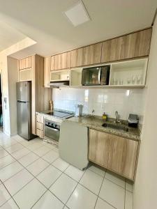 Apartamento completo e encantador في ريبيراو بريتو: مطبخ مع دواليب خشبية وثلاجة حديد قابلة للصدأ