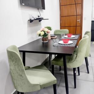 a dining room table with green chairs and flowers on it at Flat Aeroporto Internacional de GRU 4 in Guarulhos