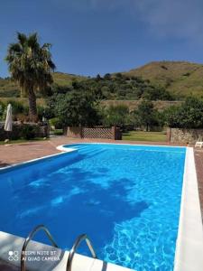 ein blauer Pool mit einer Palme im Hintergrund in der Unterkunft I Casali in Calatabiano