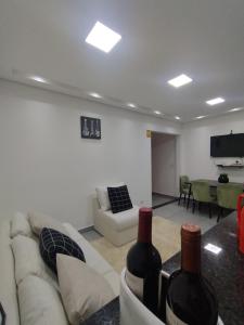 a living room with a couch and two bottles of wine at Flat Aeroporto Internacional de GRU 6 in Guarulhos