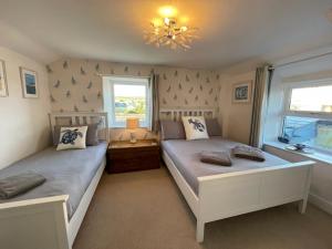 a bedroom with two beds and a chandelier at Sandown 4 bedroom house St Teath in Saint Teath
