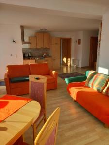 - un salon doté d'un mobilier orange et d'une table dans l'établissement Haus am Waldrand, à Thiersee
