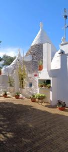 un edificio blanco con macetas al costado. en La valle dei trulli, en Villa Castelli