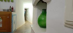 un jarrón verde sentado en la esquina de una pared en La valle dei trulli, en Villa Castelli