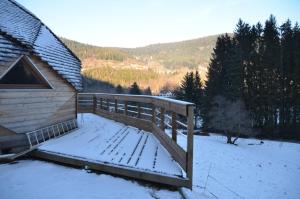 una terraza de madera con nieve junto a una casa en Les habitats de la chaume, en Plainfaing