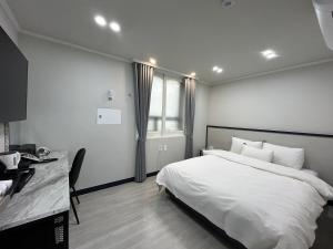 a bedroom with a bed and a desk and a window at Hotel Bom in Mokpo