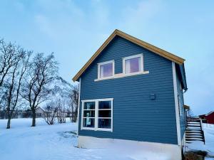 a blue house in the snow with a mountain at Panorama Valley Lofoten in Bøstad