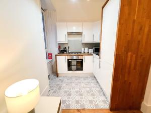 a small kitchen with white cabinets and a tile floor at Central Edinburgh, Quirky & Modern 1 bed apartment in Edinburgh