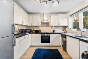 a kitchen with white cabinets and a blue rug at Comfy 4-Bed in Bristol - Garden - Sleeps 10 in Bristol