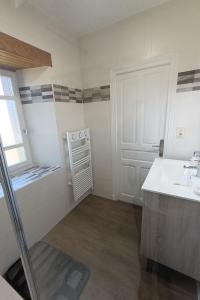 a white bathroom with a sink and a door at GITE 6 personnes à Pailherols in Saint-Clément