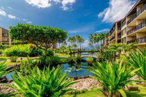 een uitzicht op een resort met een vijver en palmbomen bij Papakea C208 in Kahana