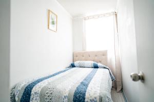 a bedroom with a bed with a blue and white quilt at Bonito departamento a pasos del Movistar Arena. in Santiago