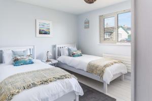 two beds in a white room with a window at Wooda Farm Holidays in Bude