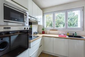 cocina con armarios blancos, fregadero y microondas en Le Bretagne- 2 chambres-Parking- Place de Bretagne, en Rennes