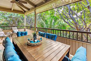 a porch with a wooden table and blue chairs at Ekolu 1602 in Wailea