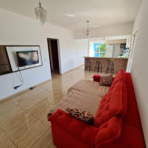 uma sala de estar com um sofá vermelho e uma cozinha em Casa em condomínio Ninho Verde 1 em Porangaba