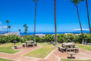 a park with two picnic tables and palm trees at Ekolu 1602 in Wailea